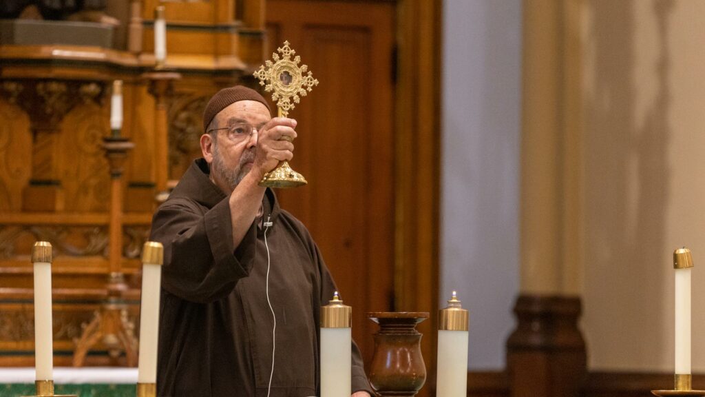 Friar David Preuss, OFM Cap. blesses the congregation with a relic of the True Cross.