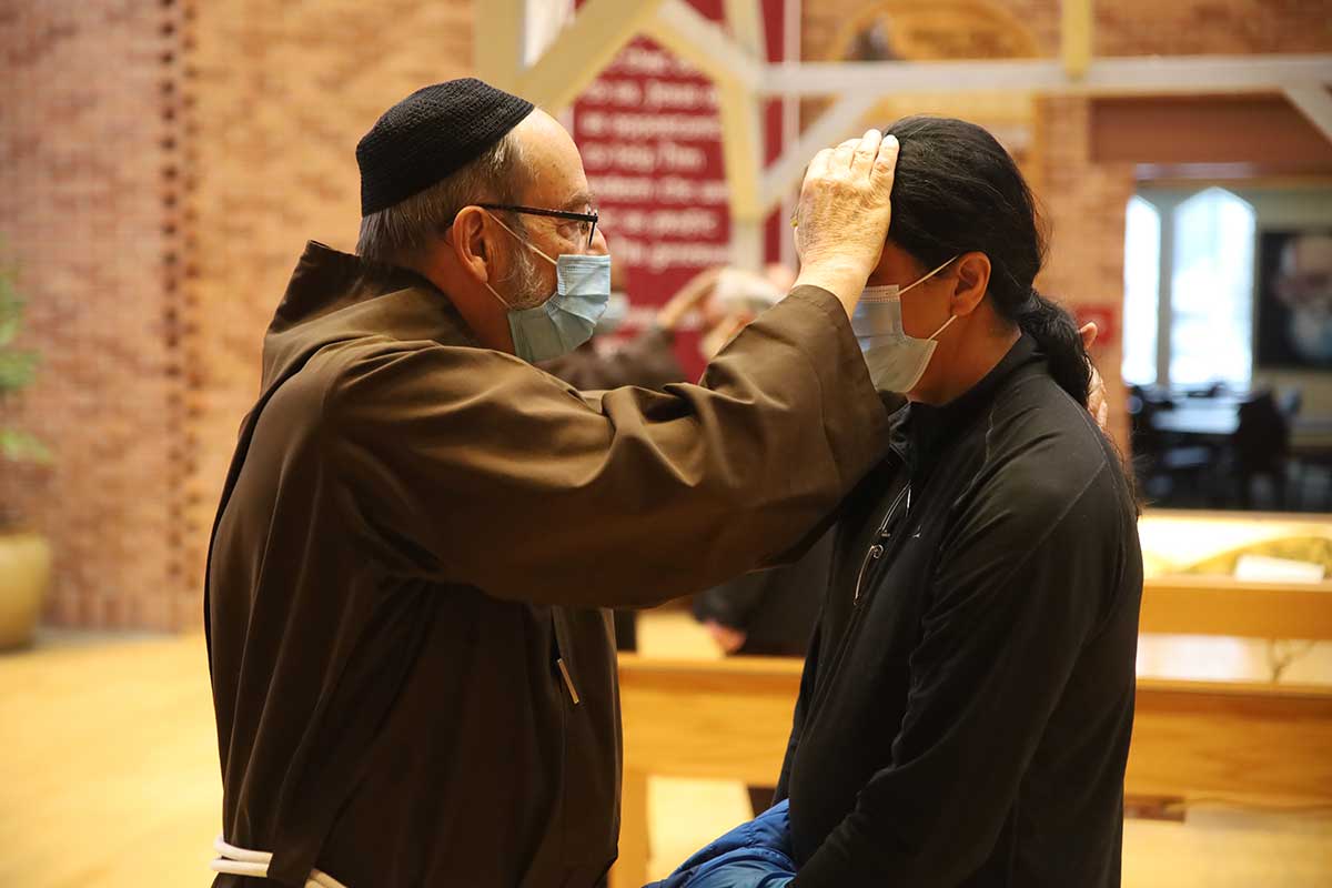 Fr. David Preuss, OFM Cap. blesses a pilgrim with a relic of the True Cross during the Blessing of the Sick service at the Solanus Casey Center