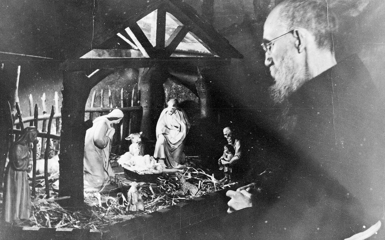 A black-and-white historic photograph depicting Blessed Solanus Casey adoring the Christ child in a manger scene.