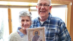 Color photo of Janet and Pat posing with an icon of Blessed Solanus Casey.