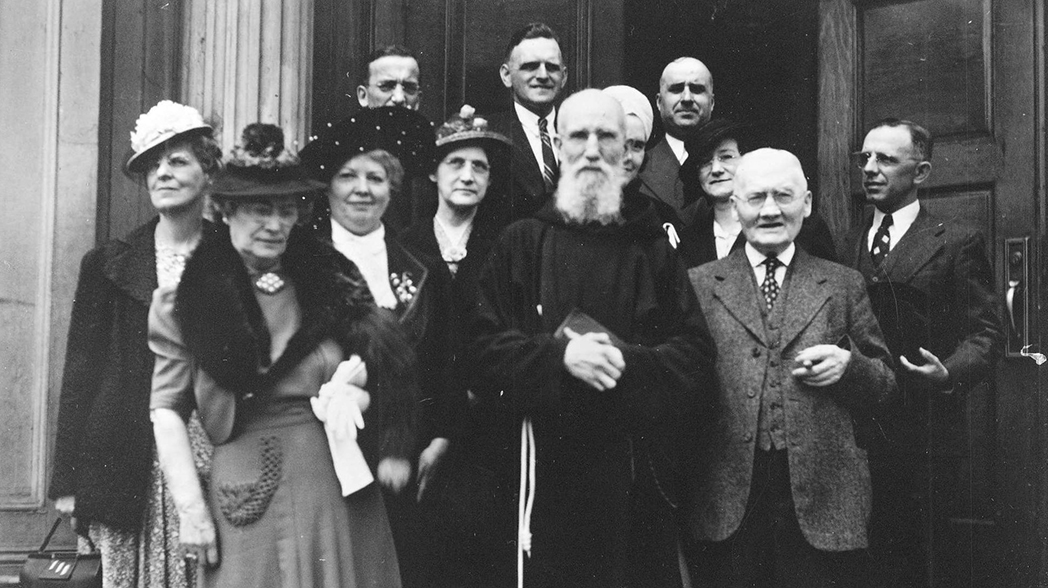Father Solanus standing with a group of parishioners in front of parish doors.
