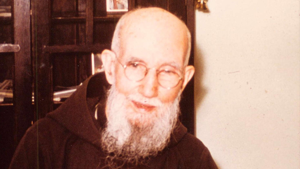 Blessed Solanus Casey smiles behind his desk.